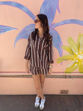 Load image into Gallery viewer, Woman in a striped outfit standing in front of a colorful mural.