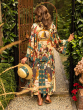 Load image into Gallery viewer, A person wearing a multicolored floral kimono robe with text and decorative elements, walking through a garden.