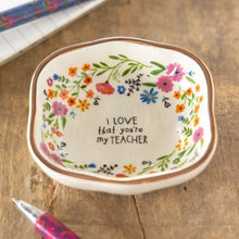 Load image into Gallery viewer, A small decorative ceramic dish with a floral border and the printed message 'I LOVE that you're my TEACHER' in the center, shown on a wooden surface with pens nearby.