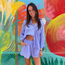 Load image into Gallery viewer, Woman in a blue outfit standing in front of a colorful mural.