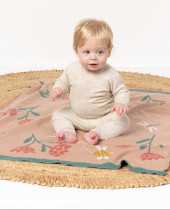 Baby sitting on a floral blanket