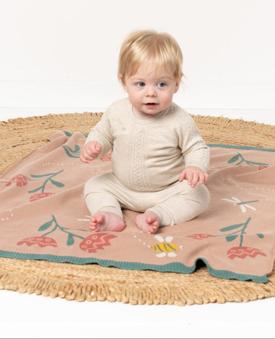 Baby sitting on a floral blanket