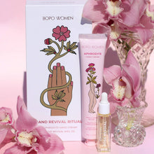Load image into Gallery viewer, BOPO WOMEN Aphrodite Hand Cream and Revival Ritual set, featuring a white illustrated box, a pink hand cream tube, and a small dropper oil bottle, styled with pink orchids in glass vases on a pink background.
