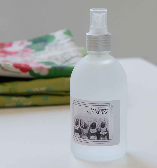 White spray bottle labeled 'Linen Spray' with a floral cloth in the background