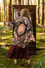 Load image into Gallery viewer, Woman in a floral kimono standing in a forest with an old wooden wardrobe.