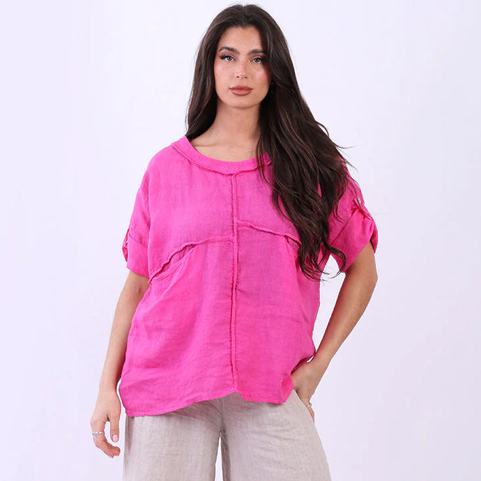 Woman wearing a bright pink top and beige pants on a white background