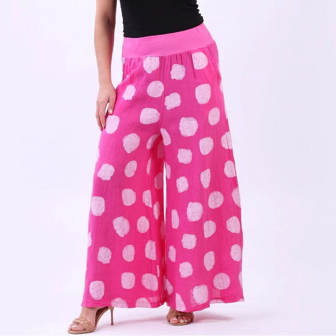Woman wearing a black top and pink polka dot pants on a white background