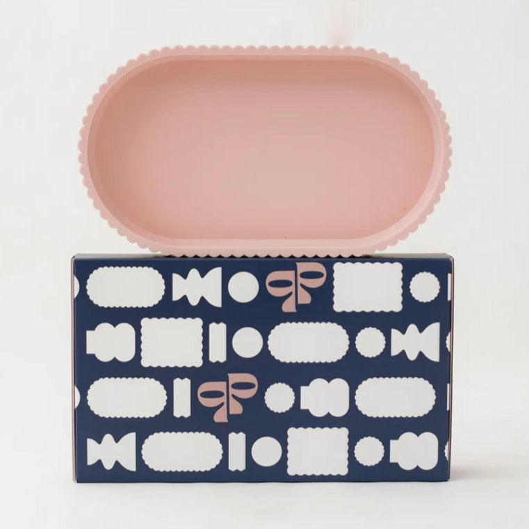Pink ribbed edge rectangular trinket dish on a navy box with white and pink patterns