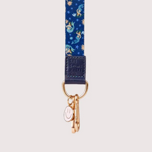 Load image into Gallery viewer, A close-up of a fabric lanyard featuring a blue background with a pattern of mermaids, stars, and suns, finished with a dark blue tab and gold-tone metal hardware.