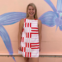 Load image into Gallery viewer, Woman wearing a red and white striped dress standing in front of a colorful mural.