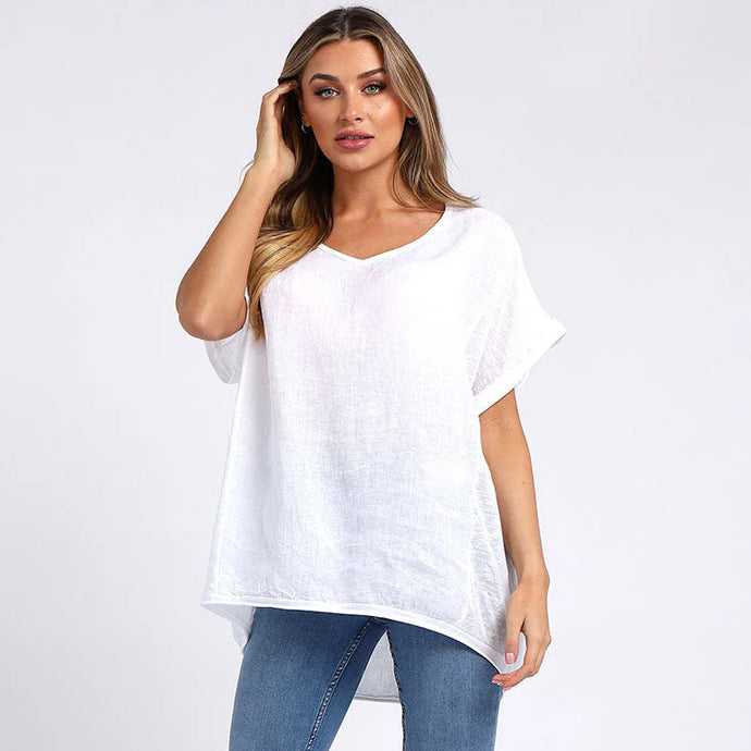 Woman wearing a white oversized linen top and blue jeans on a white background