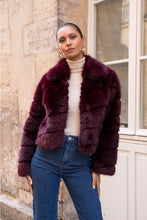 Load image into Gallery viewer, Woman wearing a faux fur coat standing against a stone wall.