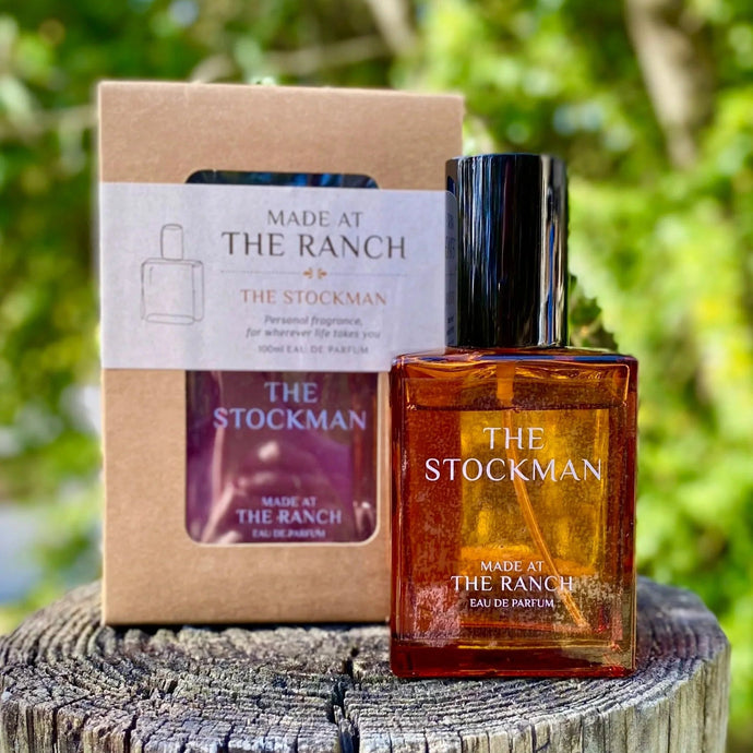 Perfume bottle and packaging labeled 'The Stockman' on a wooden surface with a natural background.