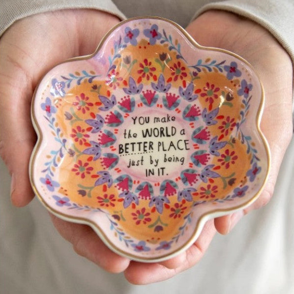 Decorative plate with floral design and text held in hands