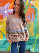 Load image into Gallery viewer, Woman wearing a beige sweater with horse print in front of a colourful mural.