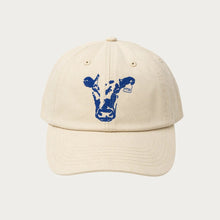 Load image into Gallery viewer, A cream-colored cotton baseball cap featuring a blue cow graphic on the front, set against a solid light gray background.